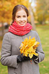 Image showing smiling woman with bunch of leaves in autumn park