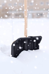 Image showing black snowshowel with wooden handle in snow pile