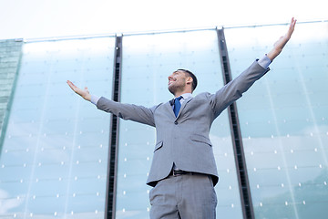 Image showing young smiling businessman over office building