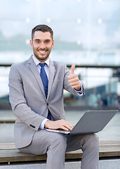 Image showing smiling businessman working with laptop outdoors