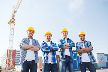 Image showing group of smiling builders in hardhats outdoors