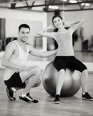 Image showing male trainer with woman doing crunches on the ball