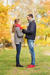 Image showing smiling couple with bunch of leaves in autumn park