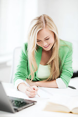 Image showing smiling student girl writing in notebook