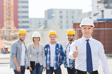 Image showing group of smiling builders in hardhats outdoors