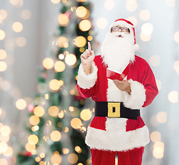 Image showing man in costume of santa claus with notepad