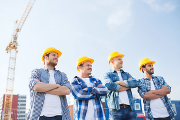 Image showing group of smiling builders in hardhats outdoors