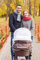 Image showing smiling couple with baby pram in autumn park