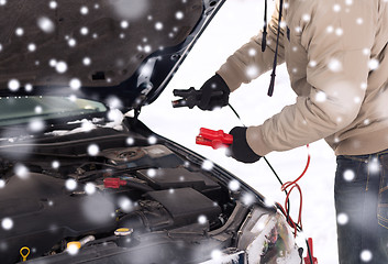 Image showing closeup of man under bonnet with starter cables