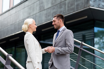 Image showing smiling businessmen shaking hands on street