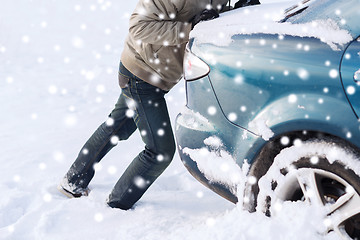 Image showing closeup of man pushing car stuck in snow