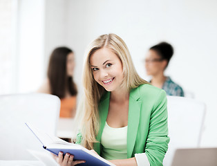 Image showing smiling student girl reading book at school