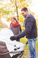 Image showing smiling couple with baby pram in autumn park