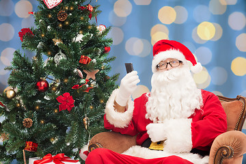 Image showing santa claus with smartphone and christmas tree