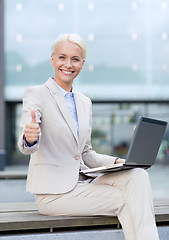 Image showing smiling businesswoman working with laptop outdoors