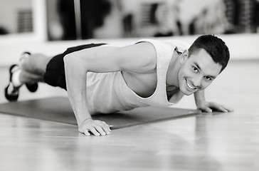 Image showing smiling man doing push-ups in the gym