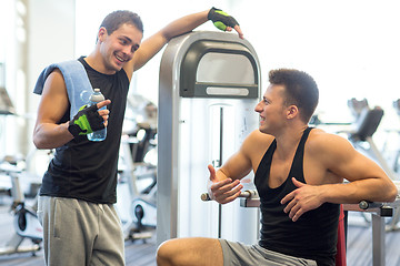 Image showing smiling men exercising on gym machine