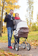 Image showing smiling couple with baby pram in autumn park