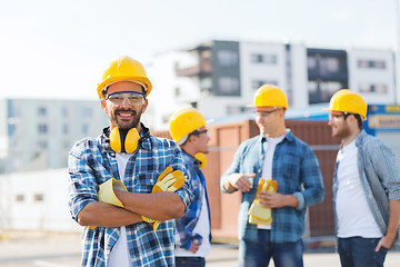 Image showing group of smiling builders in hardhats outdoors