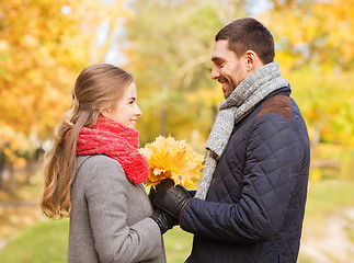 Image showing smiling couple with bunch of leaves in autumn park