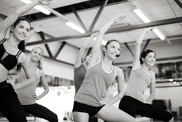 Image showing group of smiling people stretching in the gym