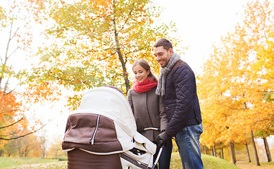 Image showing smiling couple with baby pram in autumn park