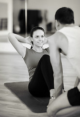 Image showing male trainer with woman doing sit ups in the gym