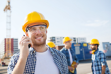 Image showing group of smiling builders in hardhats with radio