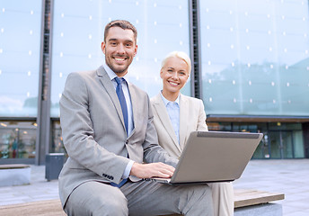 Image showing smiling businesspeople with laptop outdoors