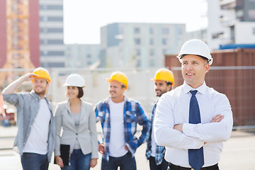 Image showing group of smiling builders in hardhats outdoors