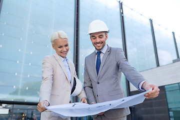 Image showing smiling businessmen with blueprint and helmets