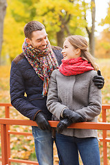 Image showing smiling couple hugging on bridge in autumn park