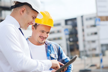 Image showing smiling builders in hardhats with tablet pc