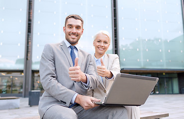 Image showing smiling businesspeople with laptop outdoors