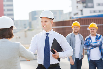 Image showing group of smiling builders in hardhats outdoors