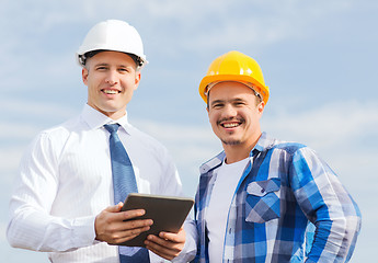 Image showing smiling builders in hardhats with tablet pc