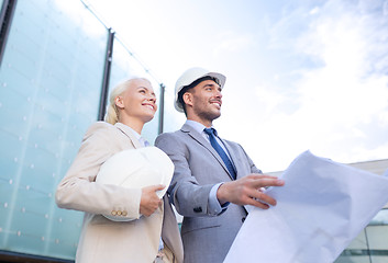 Image showing smiling businessmen with blueprint and helmets