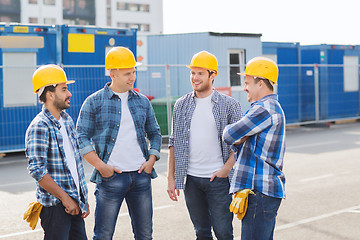 Image showing group of smiling builders in hardhats outdoors