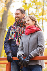 Image showing smiling couple hugging on bridge in autumn park