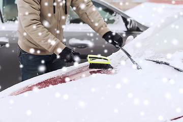 Image showing closeup of man cleaning snow from car