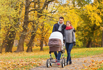 Image showing smiling couple with baby pram in autumn park