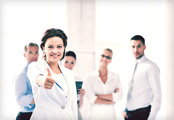 Image showing businesswoman in office showing thumbs up