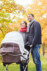 Image showing smiling couple with baby pram in autumn park