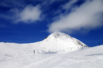 Image showing Chair-lift and ski slope at sun wind day