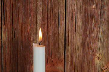 Image showing One burning candle at an old red wall