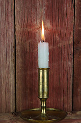 Image showing Single candle in candlestick at old wall