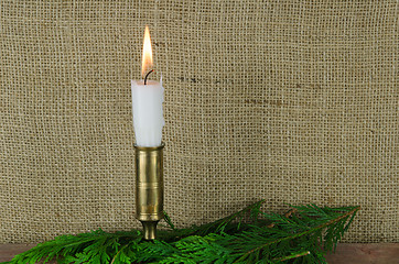 Image showing Single candle with green decoration and a burlap background