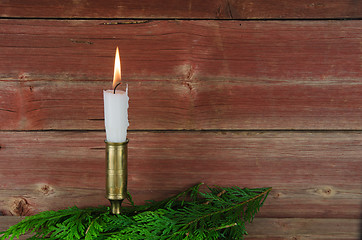 Image showing Candle at old barn wall and green decoration