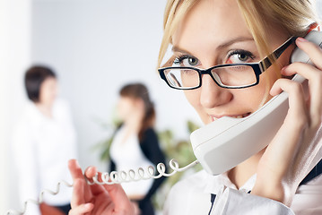 Image showing Attractive woman calls by wire phone in office