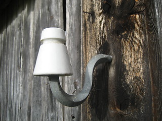 Image showing Old power cable holder on farm house wall